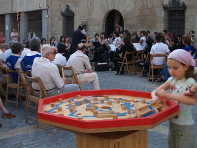 Una nena es distreu amb un joc mentre els adults escolten música.