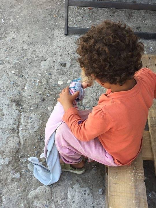 Una nena jugant amb una nina en un dels camps de refugiats a Grècia