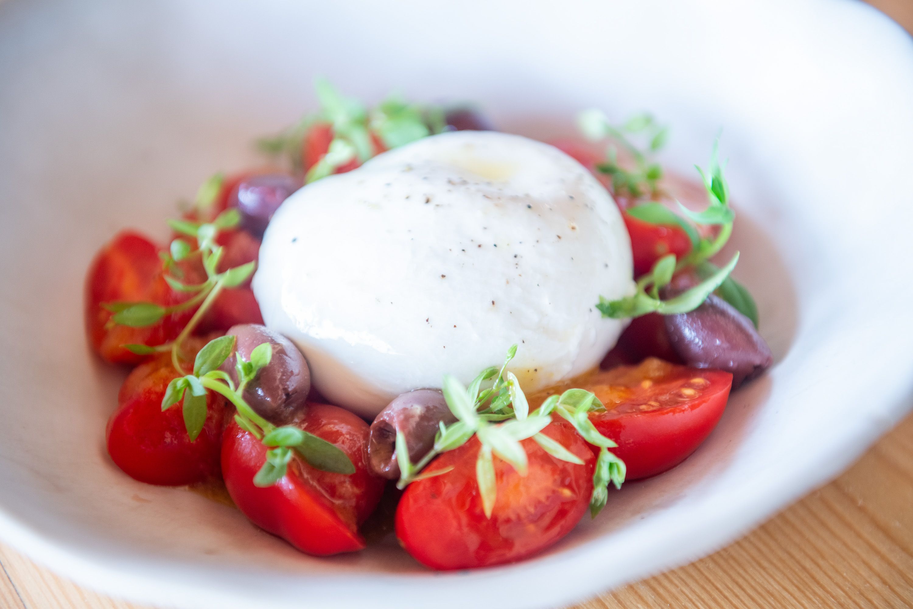 Burrata de Puglia amb tomàquets dolços datterino, vinagreta escabetxada de mel, olives kalamata i créixens d’aigua Burrata de Puglia amb tomàquets dolços datterino, vinagreta escabetxada de mel, olives kalamata i créixens d’aigua
