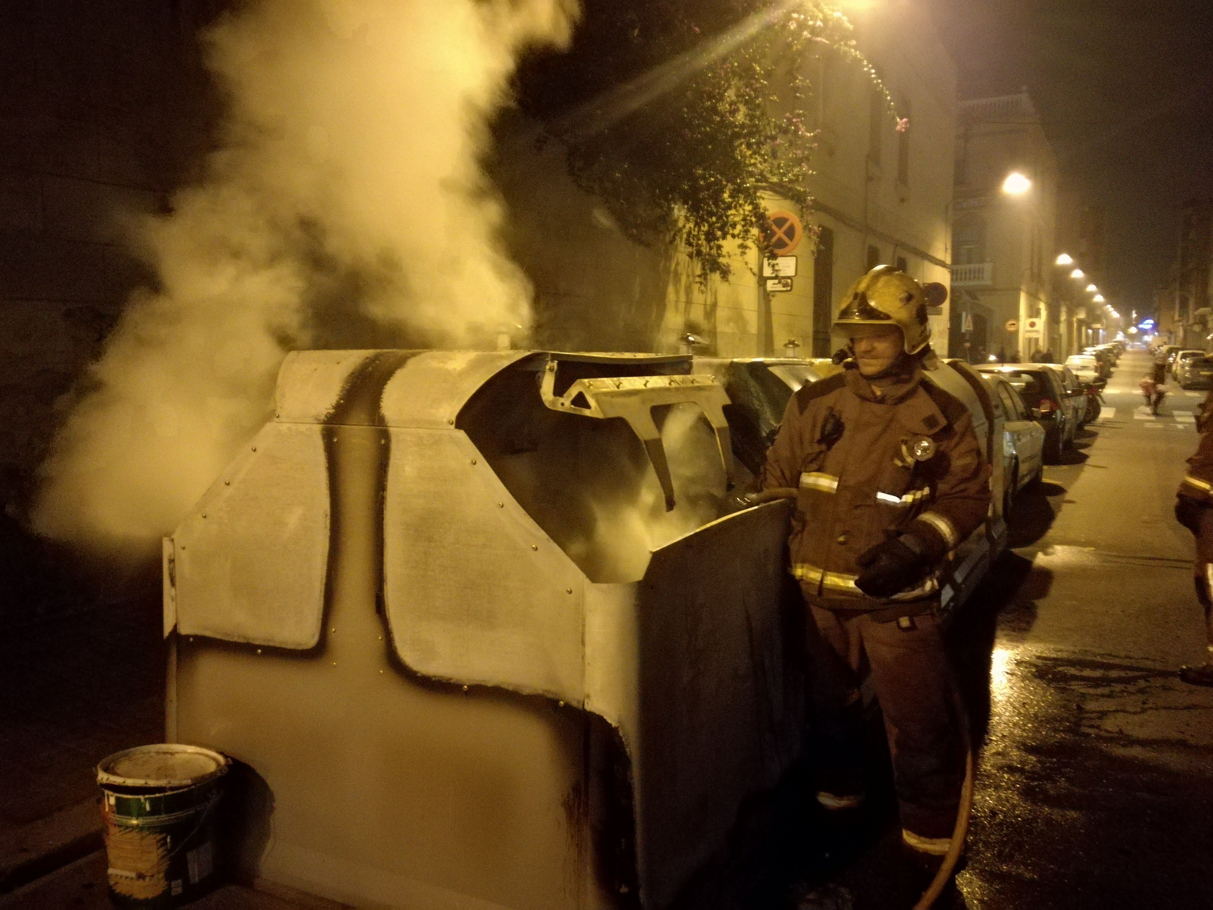Un bomber apagant el foc d'un contenidor al carrer Unió