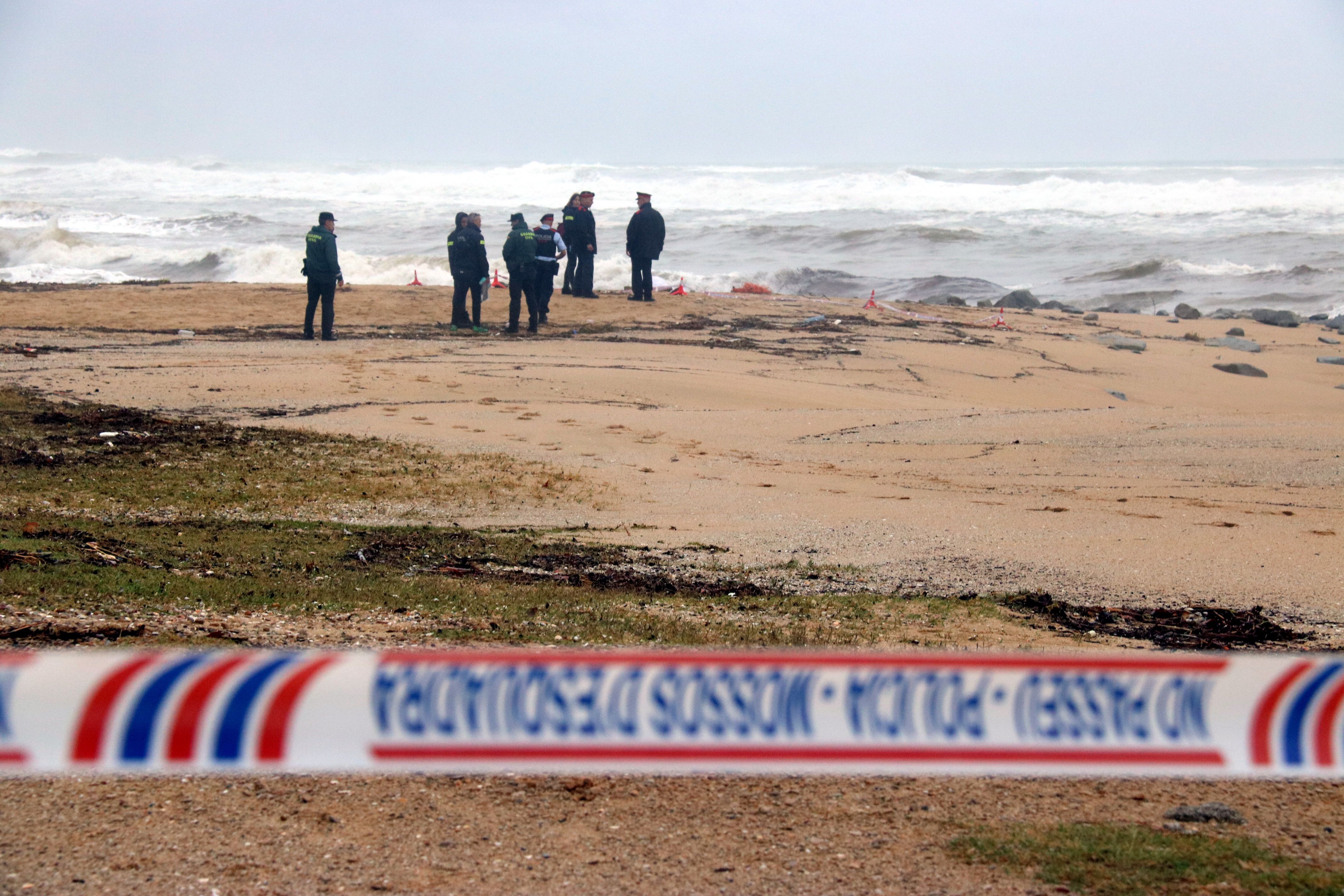 Mossos d'Esquadra i la Guàrdia Civil treballant a la platja de Caldes d'Estrac amb el cos sense vida de la víctima en segon terme. Foto: ACN Mossos d'Esquadra i la Guàrdia Civil treballant a la platja de Caldes d'Estrac amb el cos sense vida de la víctima en segon terme. Foto: ACN